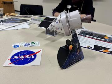 A NASA spacecraft made by scholars and display of some NASA swag available at a program event.