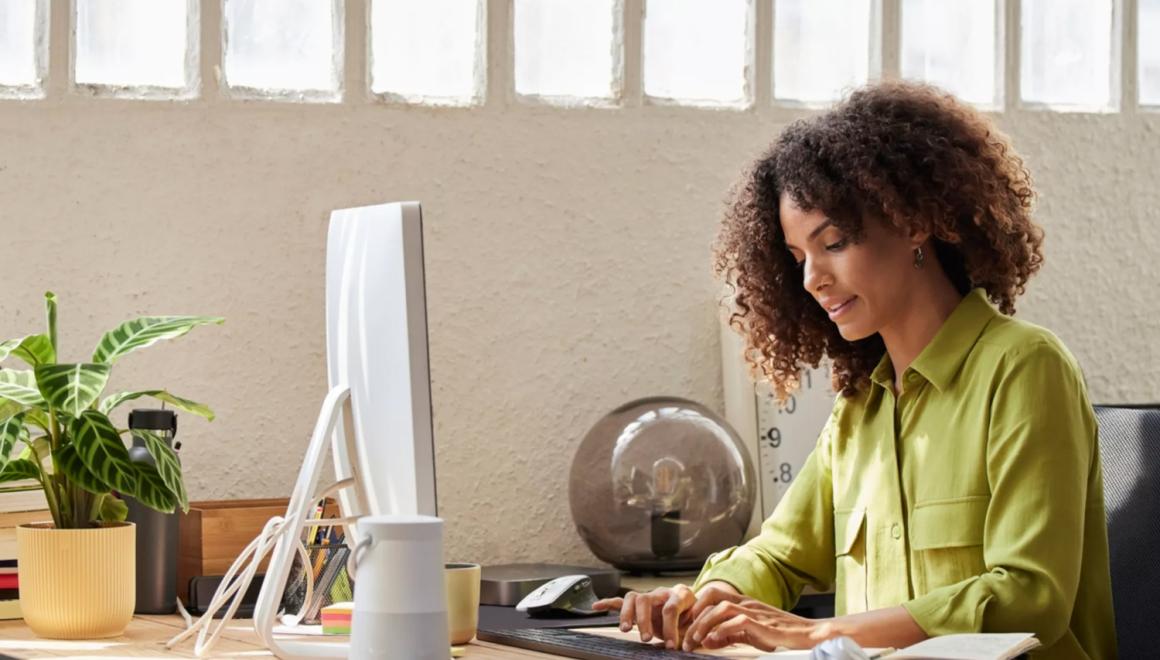 A student at a desk typing on a desktop computer keyboard