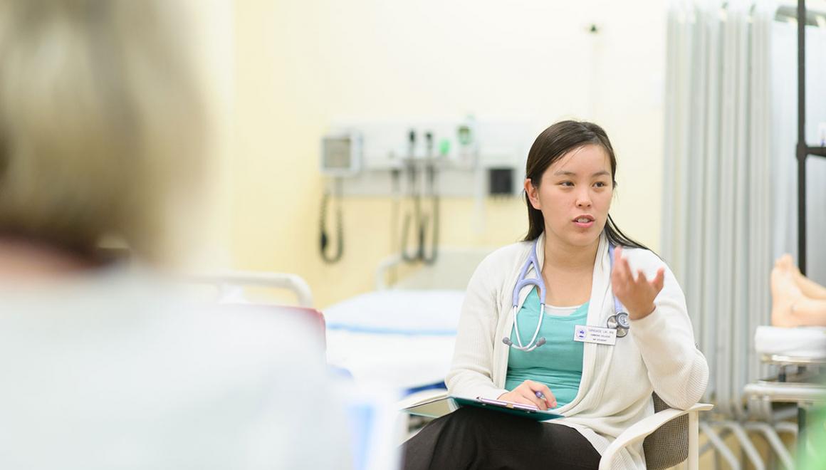 A nursing student seated in a chair and gesturing with her hand