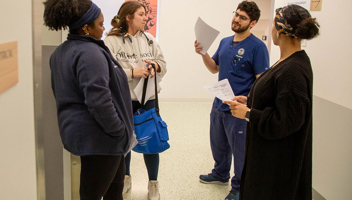 Four Simmons graduate nursing students talking in a hallway