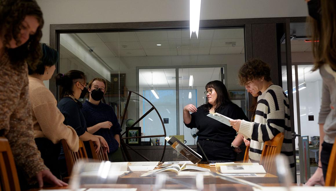 A group of Simmons students around a table covered with archival materials