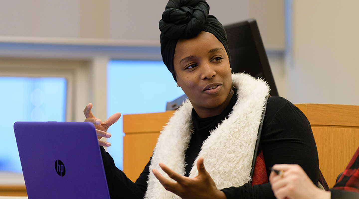 A Simmons student talking to a classmate and gesturing with their hands