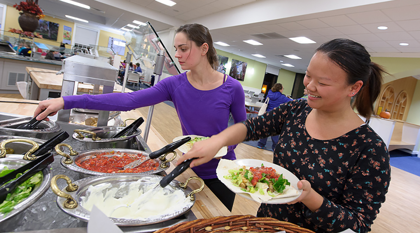 Students preparing plates at a taco bar in the dining hall