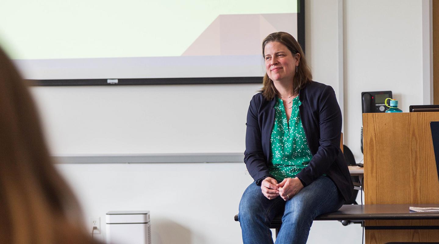 Simmons faculty member Noelle Dimitri seated on a table while engaging with a class in the Simmons School of Social Work