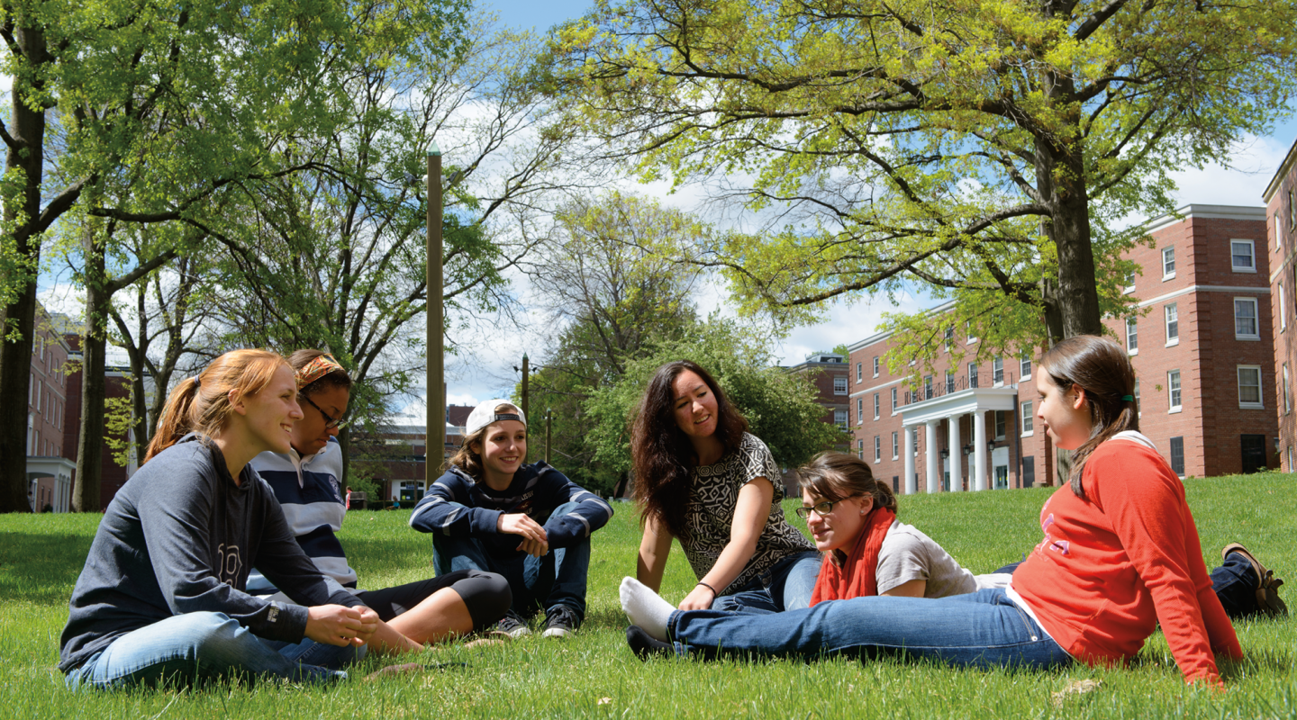 A group of Simmons students sitting in the grass on the residence campus