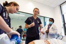 Simmons Nursing students in the simulation lab practicing a code procedure while Nursing faculty observe