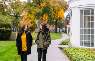 Two Simmons students walking and talking on a campus path