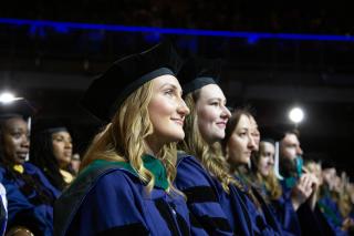 Two rows of graduate students smiling during their Commencement from Simmons University