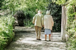 Two older adults walking on a gravel path. Photo by micheile henderson on Unsplash