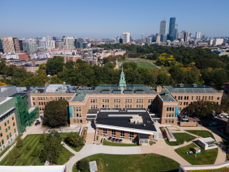 An aerial photo of the Main College Building on the Simmons campus, with the city of Boston in the background