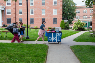 A member of the Simmons Street Team helping a family move belongings into a residence hall