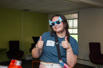 A member of the Simmons Street Team, wearing shark sunglasses, gives a thumbs up