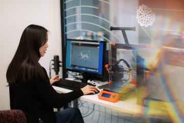 A Simmons student using a 3D printer in the Makerspace