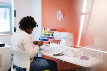 A Simmons student working at a sewing machine in the Makerspace