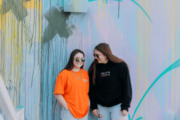 Krystianna Pietrzak (KP) ’20 and Jessie Andrew ’20 in front of a color wall of graffiti
