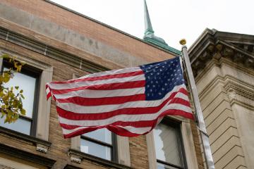 The USA flag flying next to the Main Campus Building on the Simmons University campus