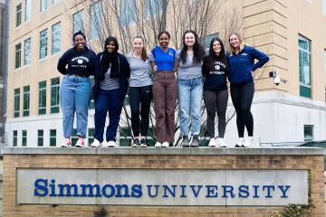 Simmons Students standing on Sign