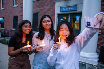 A small group of students taking a selfie at the annual candle lighting during move-in weekend