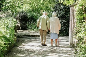 Two older adults walking on a gravel path. Photo by micheile henderson on Unsplash