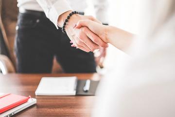 Closeup photo of two people shaking hands over the top of a desk