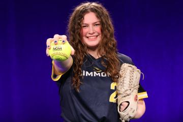 Lauren Stenmon wearing a Simmons softball uniform, holding a softball and glove