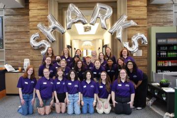 A group of 2025 orientation leaders posing in front of balloons that spell out SHARKS