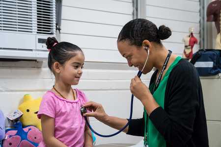 A school nurse checking the heart of a young student