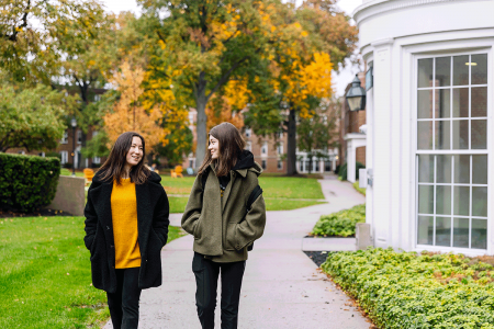 Two Simmons students walking and talking on a campus path