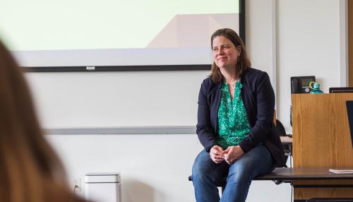 Simmons faculty member Noelle Dimitri seated on a table while engaging with a class in the Simmons School of Social Work