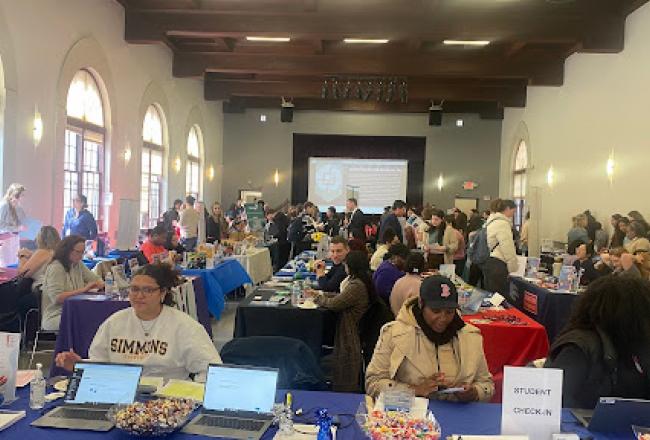 A large room set up as a career fair, with booths for employers and students to meet each other.