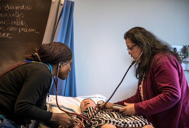 Two nursing students perform an exam on a nursing mannequin