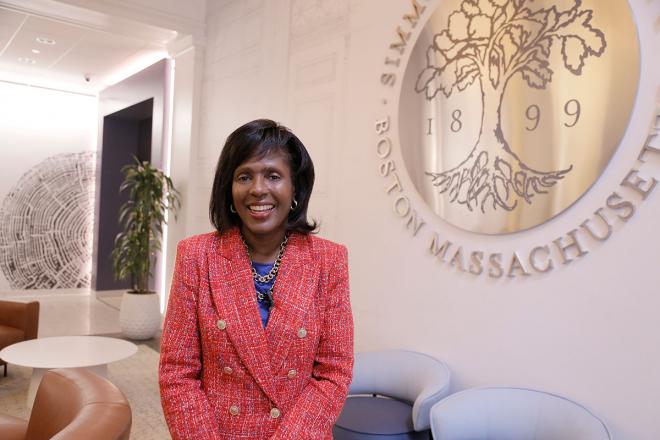 President Lynn Perry Wooten seated near a wall hanging of the University seal