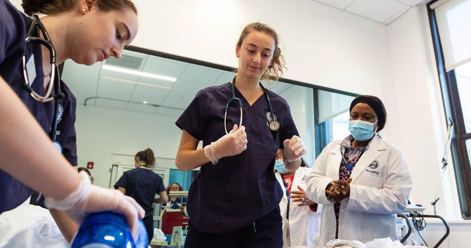 Simmons Nursing students in the simulation lab practicing a code procedure while Nursing faculty observe