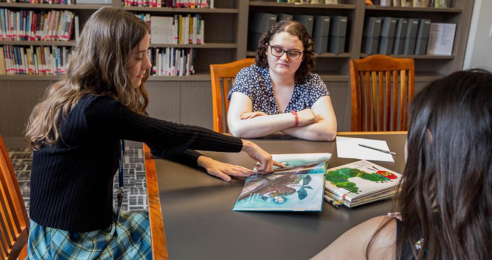 Students reading and discussing a children's literature book together