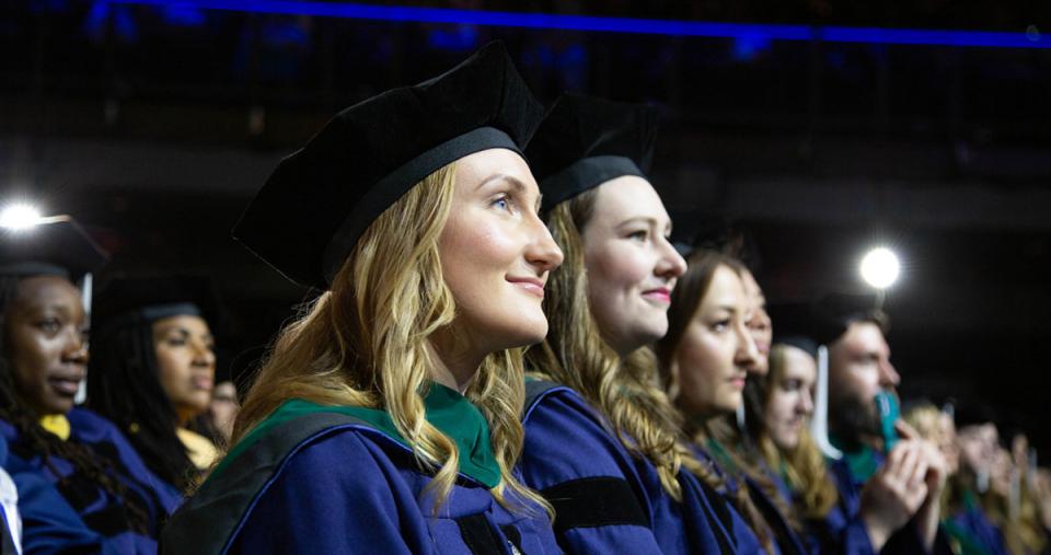 Two rows of graduate students smiling during their Commencement from Simmons University